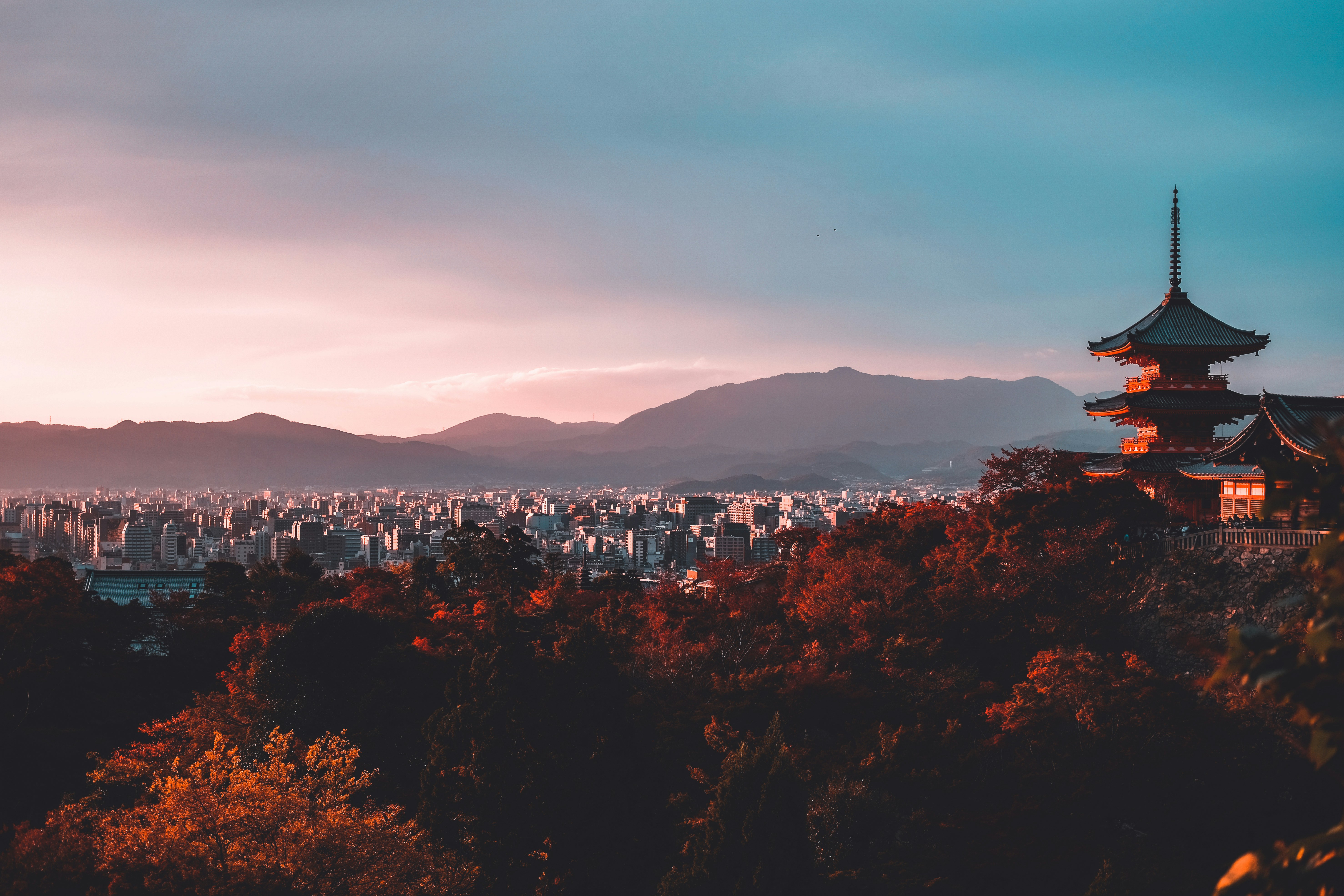 A pagoda overlooking Kyoto at sunset with autumn foliage in the foreground