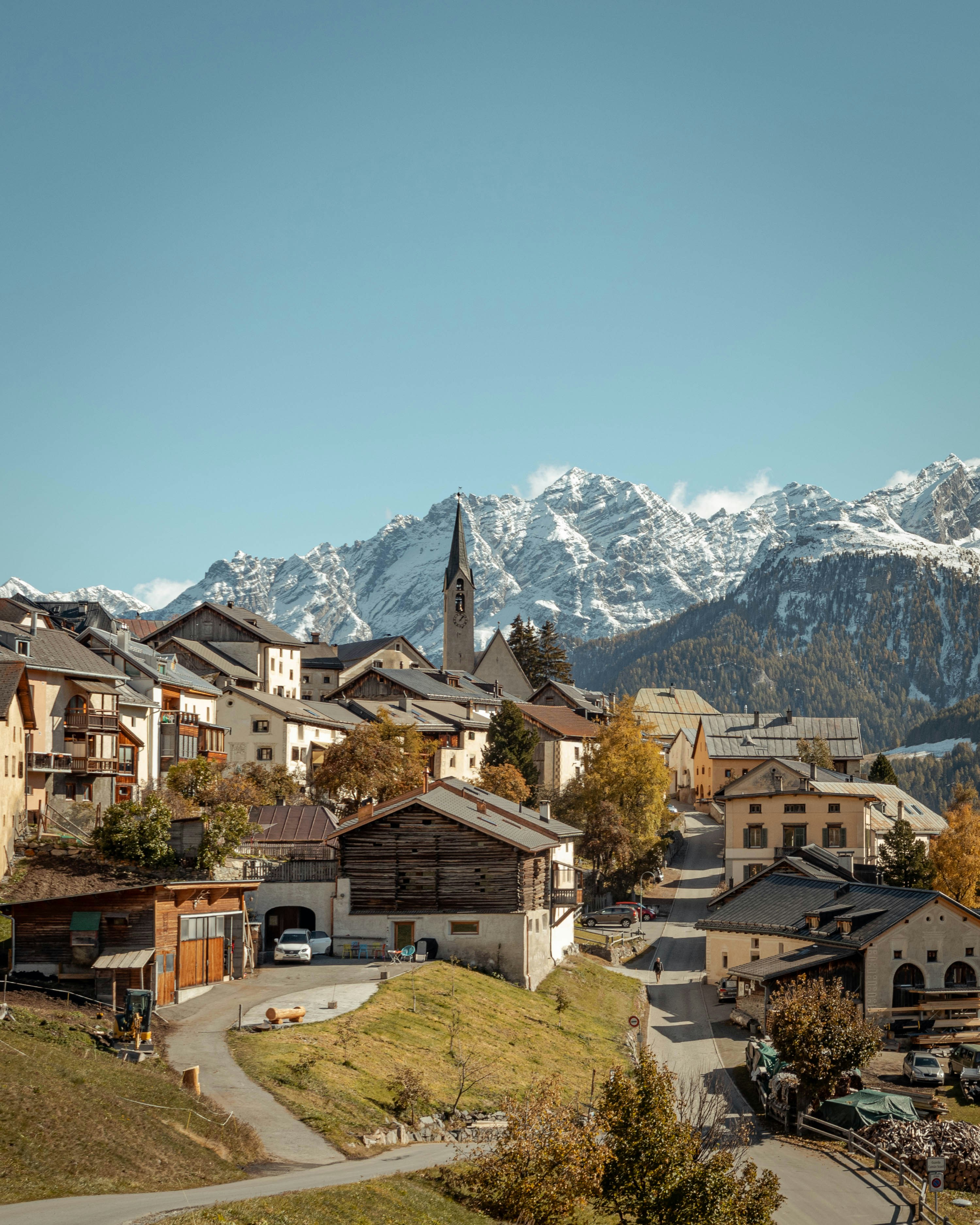 A Swiss alpine village with a church spire, set against snow-capped mountains
