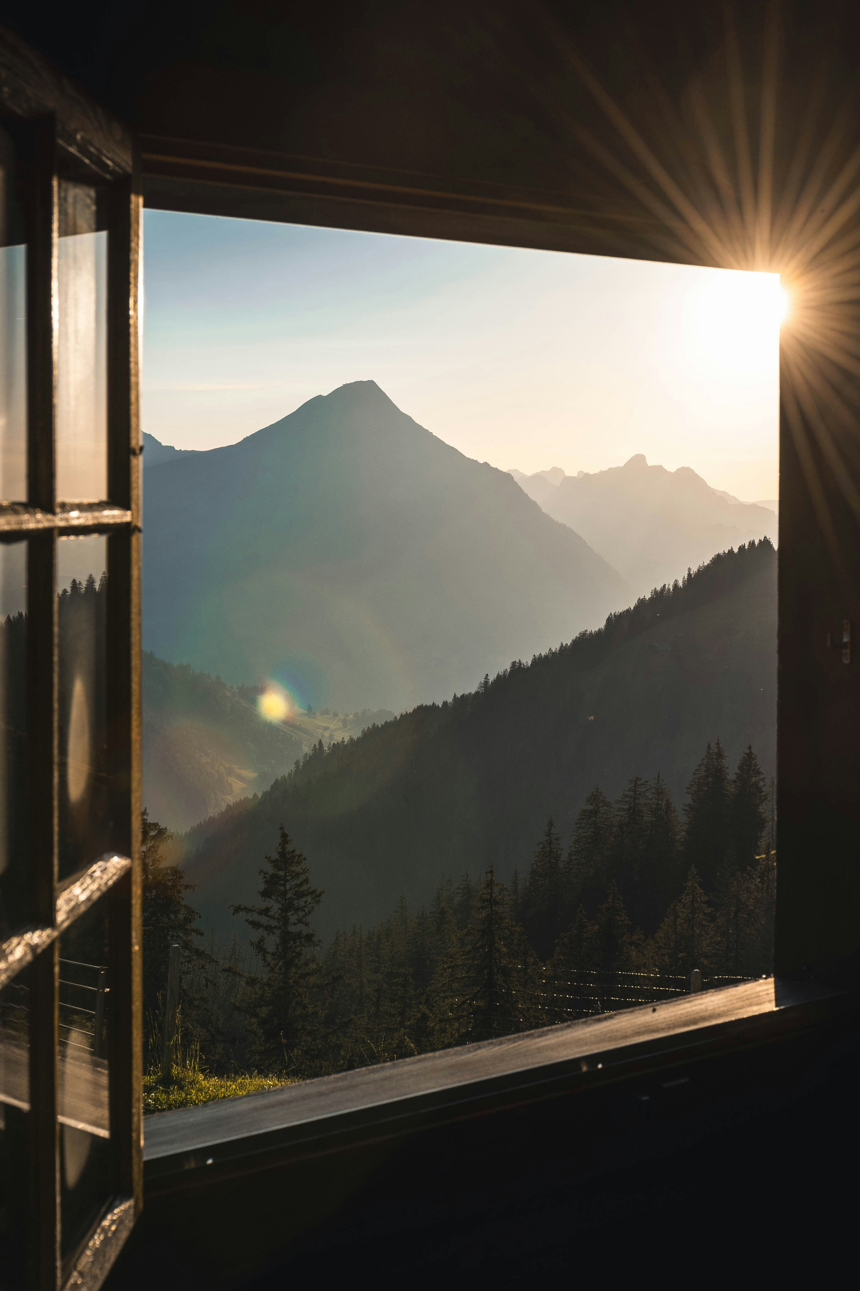 Sunrise over the Swiss Alps, viewed through an open chalet window
