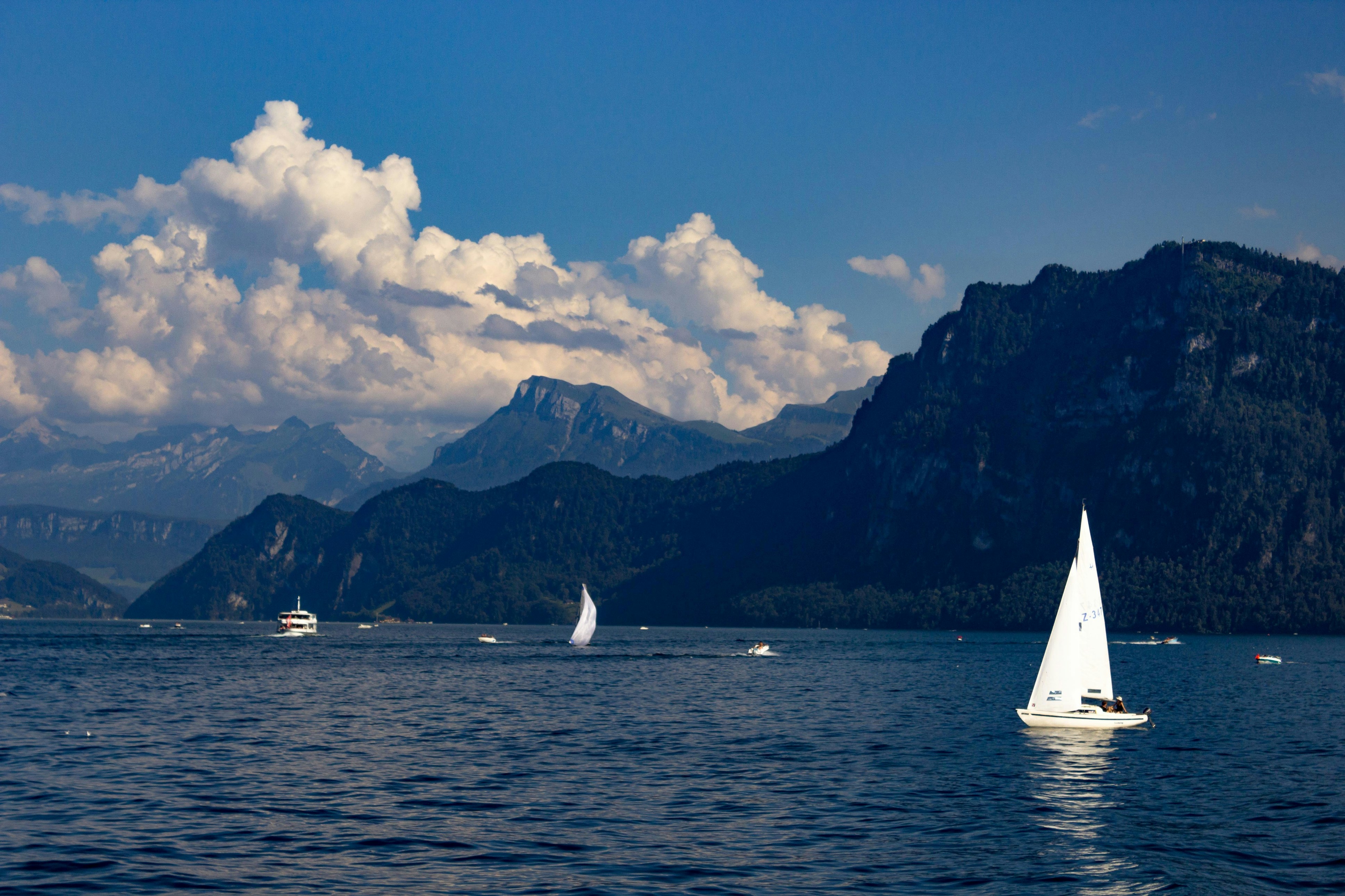 A sailboat on Lake Lucerne with the Swiss Alps rising behind it